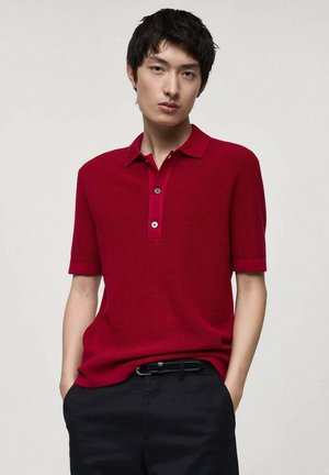 Red short-sleeve polo shirt with a ribbed texture and a two-button placket. Worn with dark pants and a black belt.