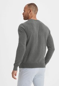 Grauer Pullover mit rundem Halsausschnitt, langen Ärmeln und gerippten Bündchen sowie Saum. Hergestellt aus weichem Material und mit einer glatten Textur versehen.