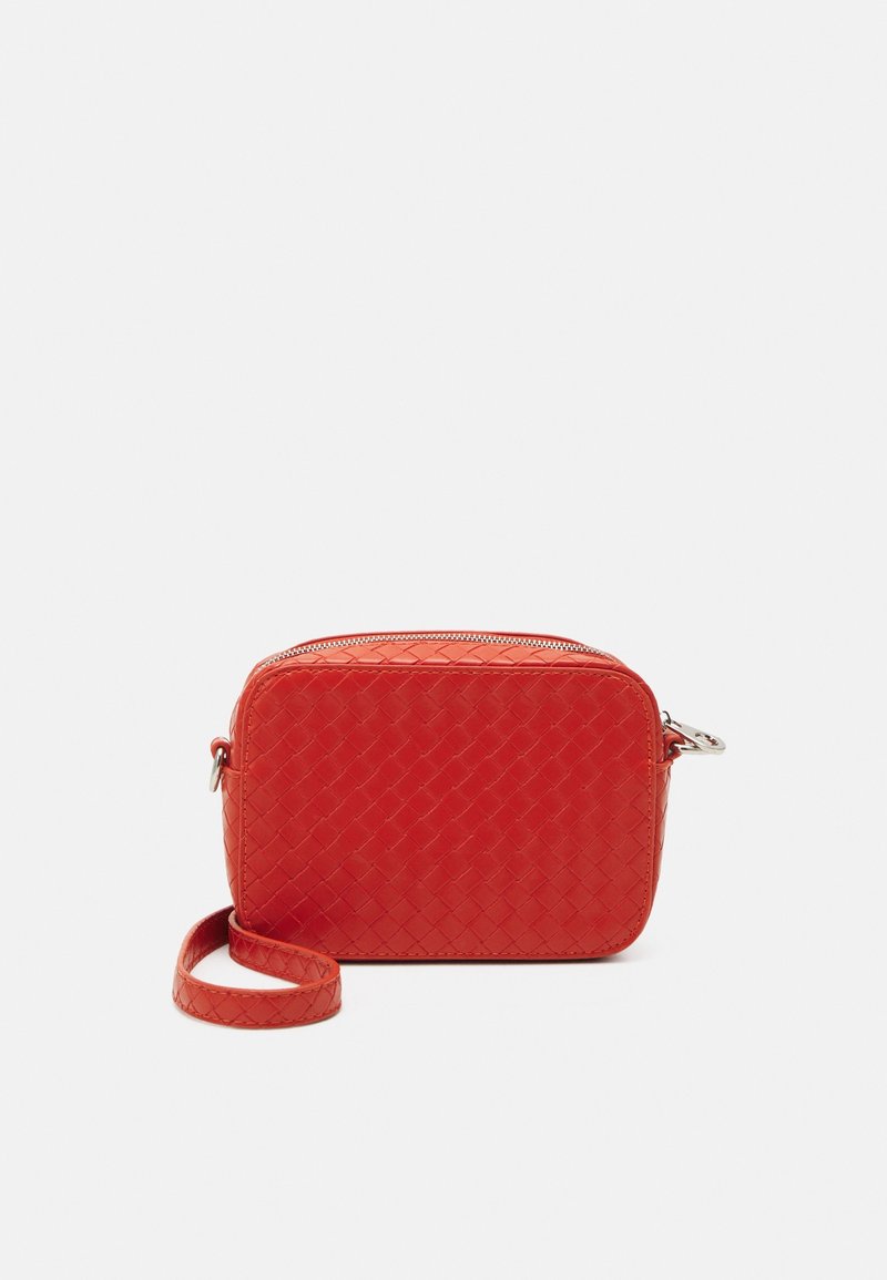 Borsa rettangolare a tracolla intrecciata rossa con chiusura a zip e tracolla abbinata posizionata accanto su sfondo bianco.