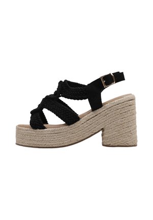 Sandale à bride tressée noire avec talon plateforme beige en tissu tissé et boucle réglable à la cheville.