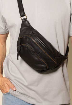Černá kožená kabelka přes rameno s volným tvarem, vybavená několika kapsami na zip, nastavitelným popruhem a jemnými zlatými kovovými doplňky.