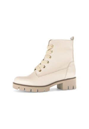 Beige ankle boots made of smooth leather with gold eyelets, round toe, and a thick, textured sole. Features a pull tab at the back.