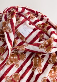 Tessuto per pigiama a righe rosse e bianche con motivo di omini di pan di zenzero, morbida texture in peluche, con cappuccio ed etichetta "NIGHTWEAR by NEXT".