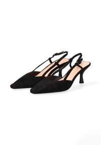 Een paar zwarte suède slingback hakken met spitse neuzen en verstelbare enkelbandjes tegen een witte achtergrond.