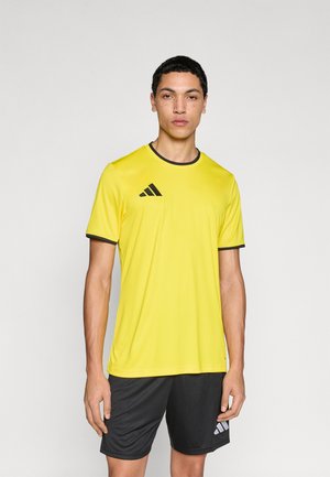 Maillot de sport jaune à manches courtes, bordé de noir autour du col et des manches, avec un logo Adidas noir sur la poitrine. Accompagné d'un short noir.