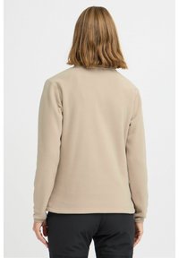 Beige fleece jasje met een zachte textuur, lange mouwen en een afgeronde zoom. Heeft een minimalistisch ontwerp en geen zichtbare sluitingen.