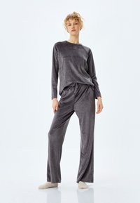 Grauvelours-Pyjama-Set mit langärmligem Oberteil mit Rundhalsausschnitt und Hose mit elastischem Taillenbund und kleinen dekorativen Punkten.