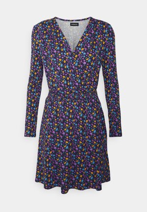 Donkerblauwe jurk met lange mouwen, V-hals, elastische taille, bedekt met kleine kleurrijke bloemenpatronen in paars, geel, blauw en oranje.