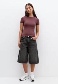 Top fitted cu mânecă scurtă de culoare mauve, asortat cu pantaloni culotte negri din denim, cu talie înaltă și încălțări sport albe cu accente gri.