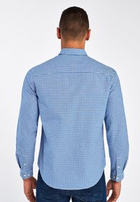 Camisa de manga larga a cuadros azul y blanca con cuello abotonado, dobladillo recto y puños decorados con detalles de botones.