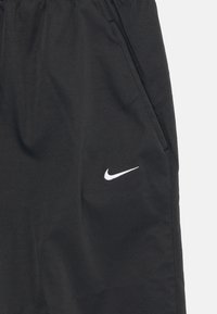 Čierne športové šortky s elastickým pásom, bočnými vreckami a bielym logom Nike swoosh na ľavej strane. Hladká, ľahká tkanina.