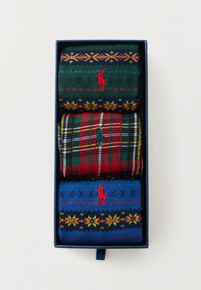 Trois paires de chaussettes colorées à motifs avec le logo Polo, soigneusement pliées dans une boîte cadeau bleu foncé sur fond blanc.