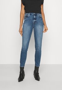 Slim-fit blå jeans i denim med medelhög midja, fem fickor och subtila blekningar. Matchas med svarta ankelboots.
