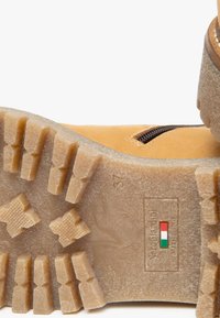 Hellbraune Lederstiefel mit einer robusten Gummisohle, die tiefe Profile aufweist. Seitlicher Reißverschluss mit einem kleinen italienischen Flaggenakzent. Größe 37.