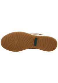 Hellbraune Lederschuhe mit einer Gummisohle, die ein Wellenmuster aufweist. Die Sohle enthält ein rechteckiges grünes Etikett mit Text.