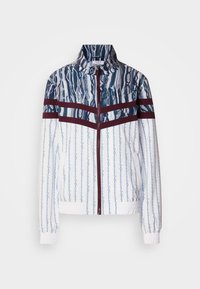 Λευκό σακάκι με μπλε κάθετες ρίγες και αφηρημένα μοτίβα. Έχει μαροκινές λωρίδες στο στήθος, ψηλό γιακά και ελαστικά μανσέτες.