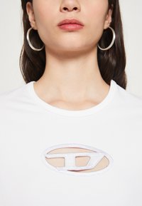 Witte katoenen t-shirt met een ronde uitsnijding en een geborduurd logo in zilver. Ronde halsontwerp en een gladde textuur.