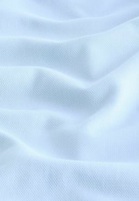 Helle blaue, strukturierte Stoff mit einem gewebten Muster, das weiche, wellenförmige Falten aufweist, die einen subtilen Glanz und Tiefenwirkung erzeugen.