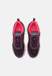 Donkerpaarse sportschoenen met roze accenten, bovenwerk van mesh, gevulde tong en dikke, gestructureerde zool. Bevat een vetersysteem voor een veilige pasvorm.