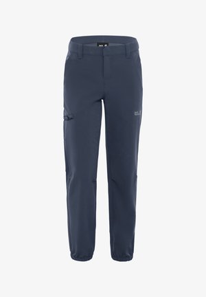 Kind trägt marineblaue Outdoor-Hose und blaue Wanderschuhe, steht mit entspannten Händen an den Seiten.