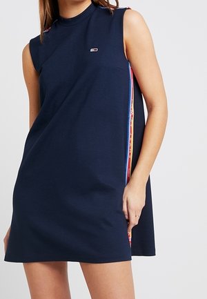 Marineblå ærmeløs kjole i bomuld med løs pasform. Har farverigt bånddetalje i siden og et lille logo på brystet.