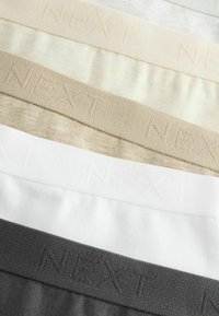 Set di elastici mostrati in beige, beige chiaro, bianco, grigio e grigio scuro con il marchio in rilievo "NEXT" lungo il bordo superiore di ciascun elastico.