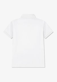 Λευκό κοντομάνικο πόλο μπλουζάκι με κλασικό γιακά, λεία υφή και χωρίς ορατά σχέδια ή εξαρτήματα. Απλή πίσω όψη.