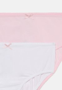 Dve súpravy dámskych nohavičiek; jedna ružová a jedna biela. Obidve sú vyrobené z jemného bavlneného materiálu s dekoračnými mašľami a vlnitým elastickým lemem.