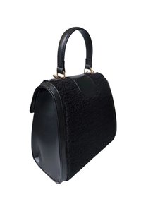 Sac à main noir avec une façade texturée, des côtés en cuir lisse et une seule poignée courbée attachée par quincaillerie dorée.