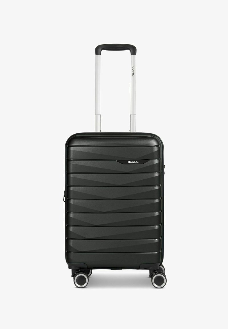 Maleta dura negra con diseño estriado, robusta asa blanca y cuatro ruedas giratorias para una fácil movilidad. Presenta un logo en la parte frontal.