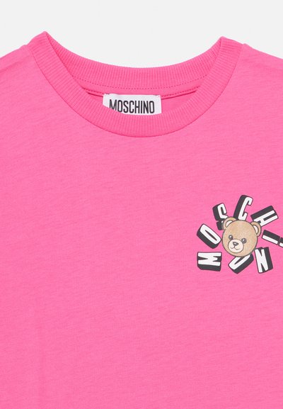 Tricou roz aprins din bumbac, cu guler rotund striat, având o grafică mică cu ursuleț și textul stilizat „MOSCHINO” pe piept.