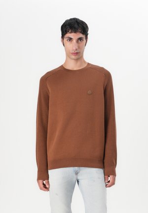Pull en tricot marron avec un col rond, des poignets côtelés et un corps texturé. Présente un petit logo sur la poitrine gauche.