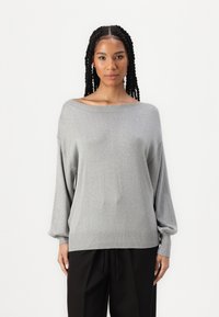 Suéter cinza, de corte largo, com um design à la off-the-shoulder. Textura suave com um brilho subtil. Punhos e bainha canelados acrescentam detalhe.