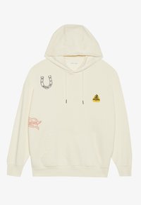 Cremefarvet hoodie med en frontlomme, der har forskellige lapper: en hestesko, en gul trekant og et rødt banner med tekst. Materialet er bomuld.