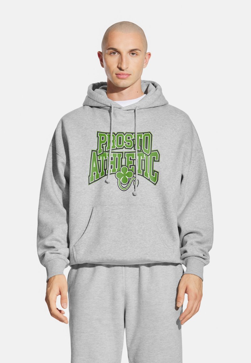 Szara bluza z kapturem, z kieszenią z przodu, sznurkiem w kapturze i grafiką "PROSTO ATHLETIC" w kolorze zielonym. W zestawie ze stonowanymi szarymi spodniami dresowymi.