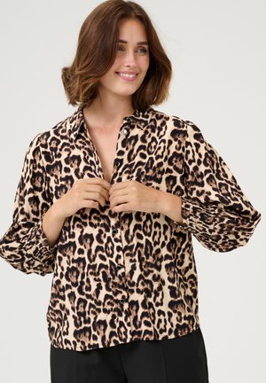 Leopard-print button-up shirt in tan and black, featuring relaxed sleeves with smocked cuffs and a classic collar. Smooth fabric texture.
