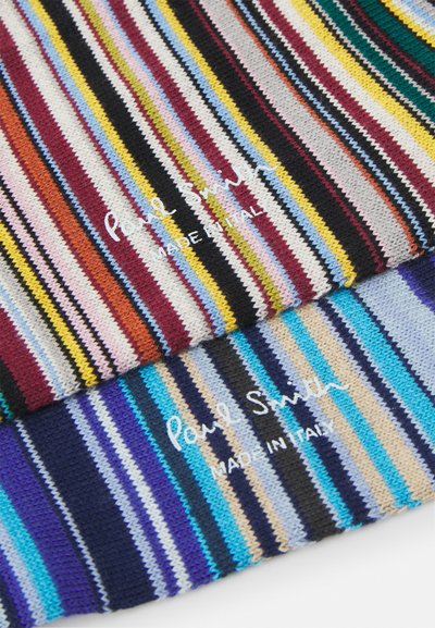 Two knit scarves feature vibrant, multicolored stripes in varying widths. Text includes "Paul Smith" and "Made in Italy" in white.