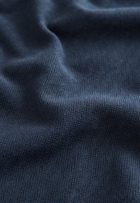 Tissu bleu marine avec un tissage texturé, présentant des motifs subtils et une apparence douce, idéal pour les vêtements ou le rembourrage.
