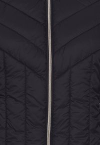 Doudoune noire à motif matelassé en chevrons, avec fermeture éclair argentée, matériau légèrement rembourré et détails de couture visibles.