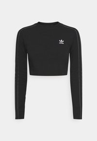 Černý dlouhý rukáv crop top vyrobený z měkké látky. Má tři šedé pruhy podél rukávů a malé bílé logo Adidas na hrudi.