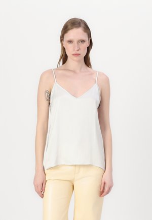 Light gray camisole with thin adjustable straps, a V-neckline, and smooth, sleek fabric. Paired with glossy yellow pants.