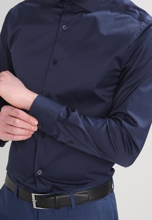 Navyblauw overhemd van een soepele stof, met een knoopsluiting aan de voorkant en lange mouwen. Heeft bijpassende knopen en een klassiek kraagontwerp.