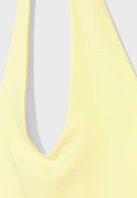 Haut sans manches jaune clair avec un profond décolleté arrondi sur un fond blanc uni.