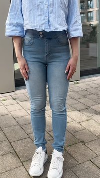 Svetlo modri pambasti jeans z visokim pasom, dvema sprednjima žepoma in oprijetim krojem. V kombinaciji z belimi športnimi čevlji in srajco s plavimi črtami.