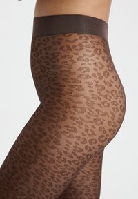Collant opachi realizzati in materiale trasparente con un motivo a stampa leopardata marrone. Ampia cintura marrone con una texture liscia.