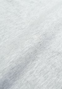 Tessuto grigio chiaro con una texture liscia, leggermente melange. La trama appare morbida, con fibre visibili e sottili variazioni sulla superficie.