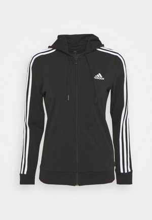 Haut à capuche zippé noir avec un cordon de serrage, arborant des rayures blanches sur les manches et un logo brodé sur la poitrine.