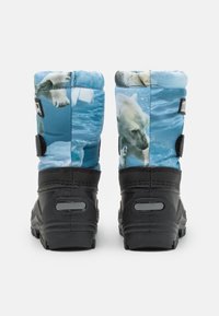 Botas de nieve con una parte superior de tejido azul que presenta imágenes de osos polares, suelas de goma negras y correas ajustables en los laterales.