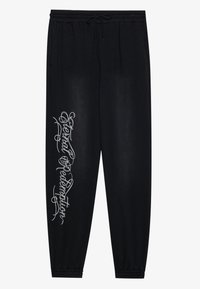 Black sweatpants with an elastic waistband, side pockets, and a silver graphic text design on the left leg. Soft fabric with a smooth texture.