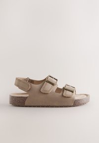 Sandalo in camoscio marrone con due fibbie regolabili, suola in sughero testurizzata, design posteriore aperto e suola piatta per il massimo comfort.